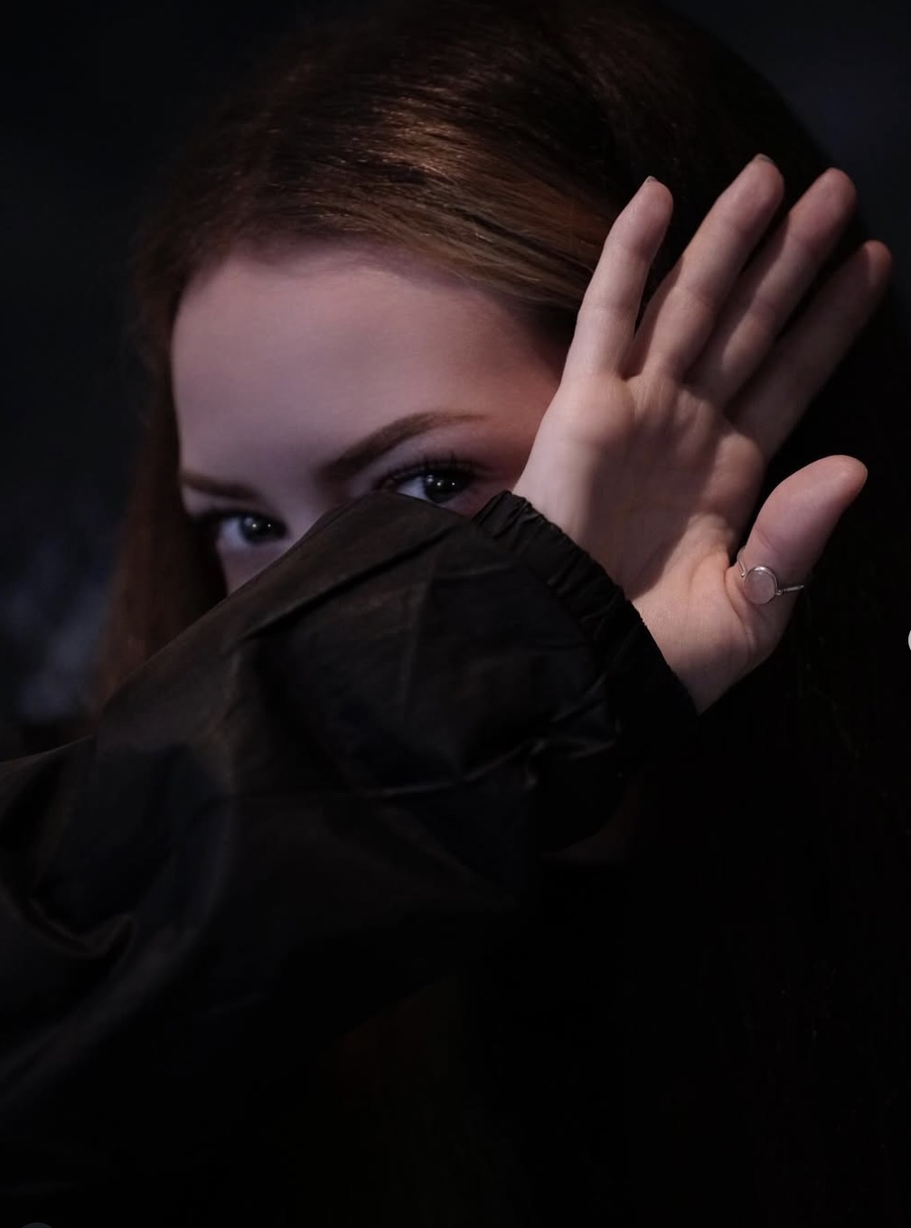 Dark fashion portrait of a woman raising her hand